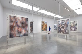 People in exhibition of abstract paintings held in place with metal frames. Julie Mehretu