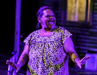 An Aboriginal woman in a printed blouse is laughing.