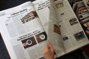 Alana Hunt, 'Cups of nun chai’, 2010-20 which explores the ongoing territorial conflict in Kashmir. Photo: Courtesy of the Artist. A hand flicking a newspaper.